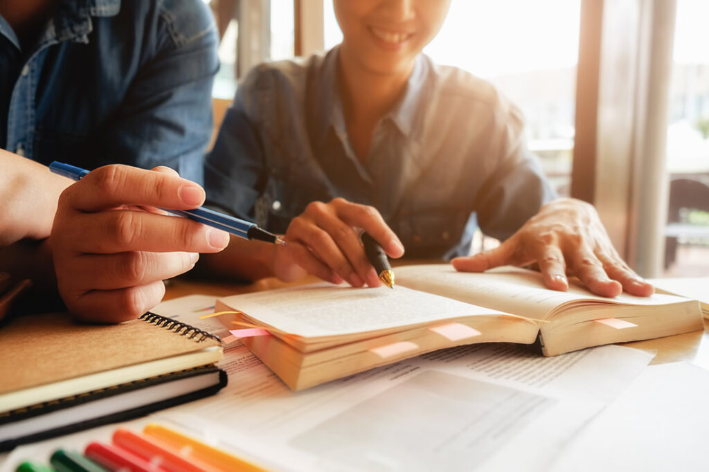 conceito-de-educacao-estudante-estudando-e-brainstorming-conceito-de-campus-perto-de-estudantes-discutindo-seu-assunto-em-livros-ou-livros-didaticos-foco-seletivo_or
