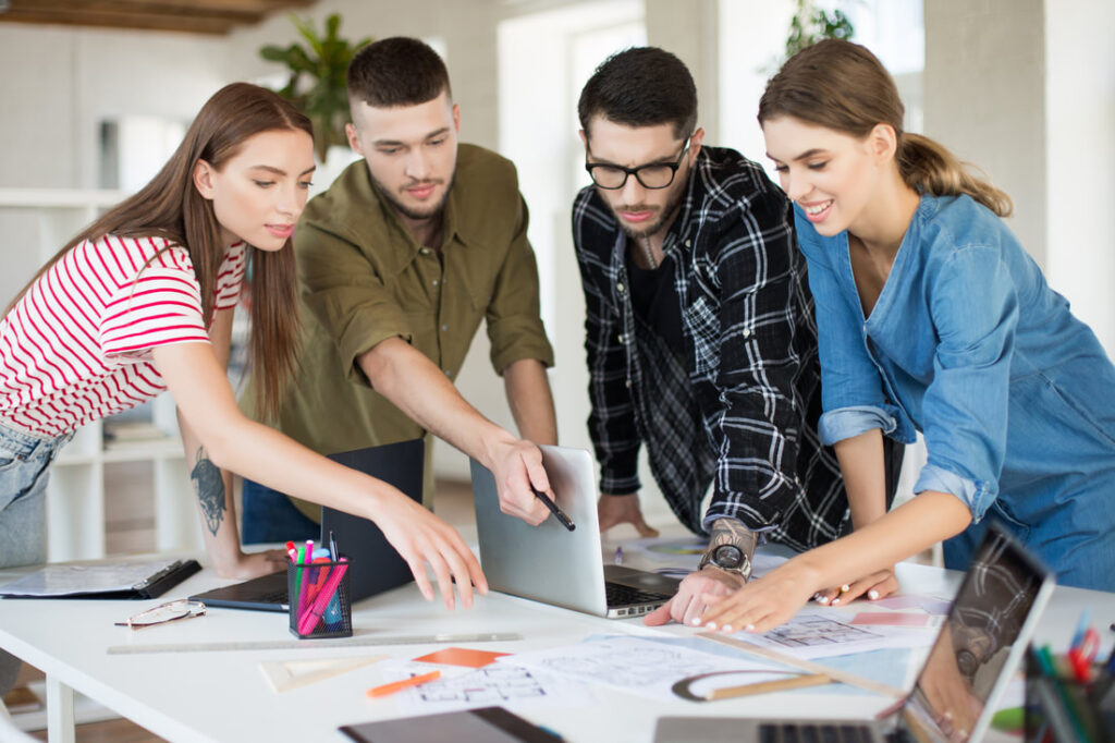 jovens-criativos-trabalhando-juntos-com-laptop-grupo-de-caras-legais-trabalhando-em-um-novo-projeto-enquanto-passam-tempo-no-escritorio-moderno_orig
